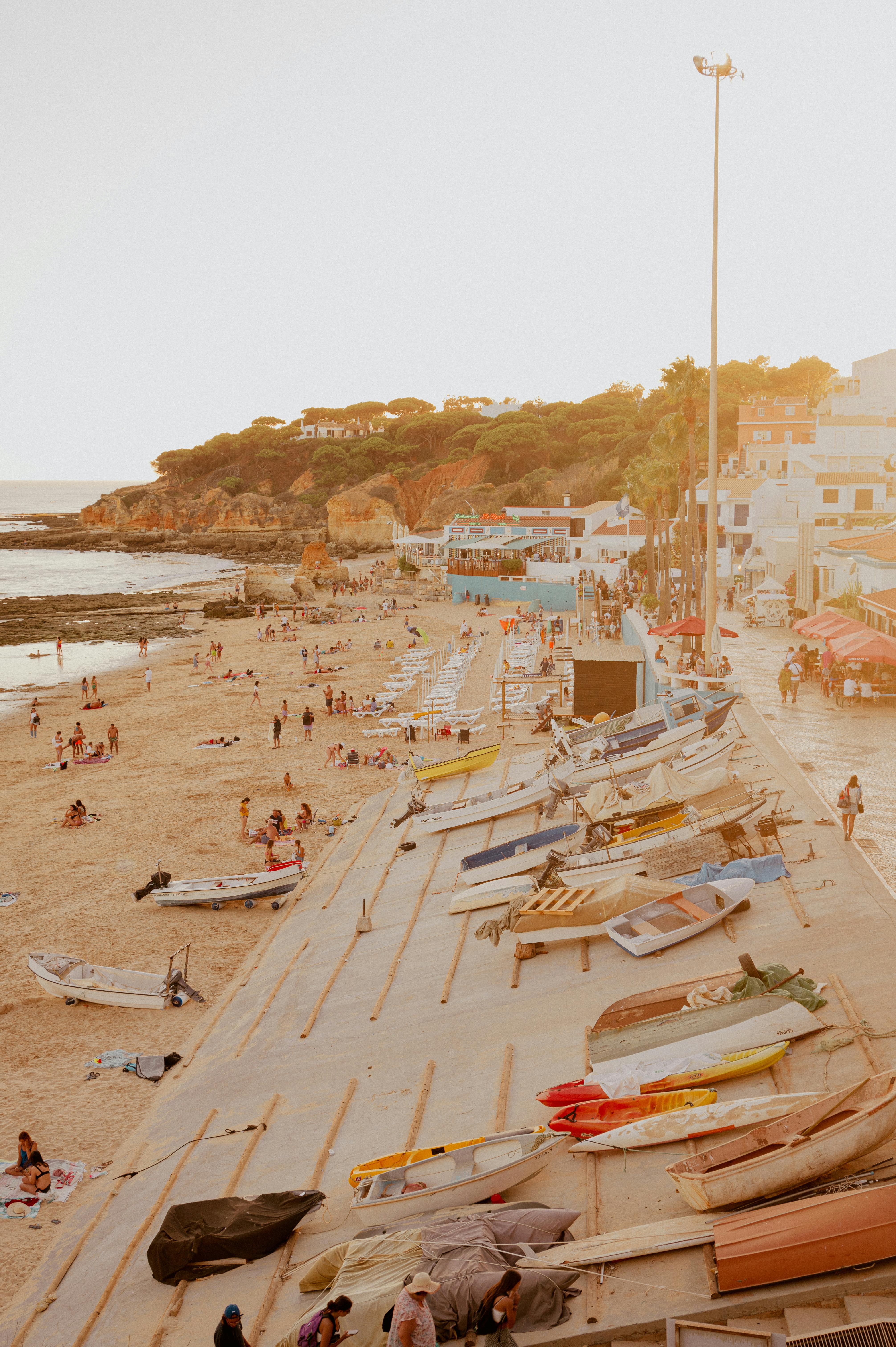 Captivating beachfront scene with boats, tourists, and sandy coastline at sunset.