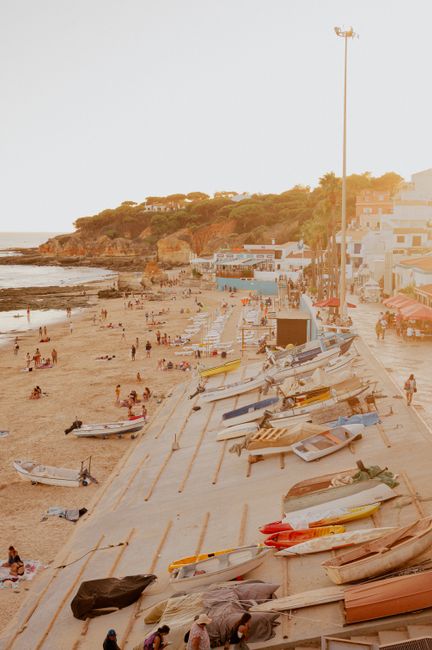 Captivating beachfront scene with boats, tourists, and sandy coastline at sunset.