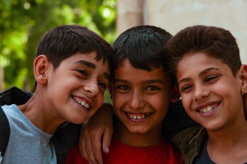 Free A joyful portrait of three smiling boys with short hair standing closely together outdoors. Stock Photo