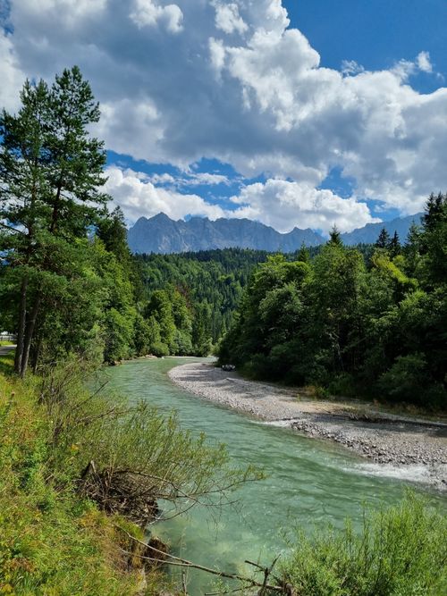 Free Peaceful river winding through vibrant green forest under a dramatic sky. Perfect for nature backgrounds. Stock Photo