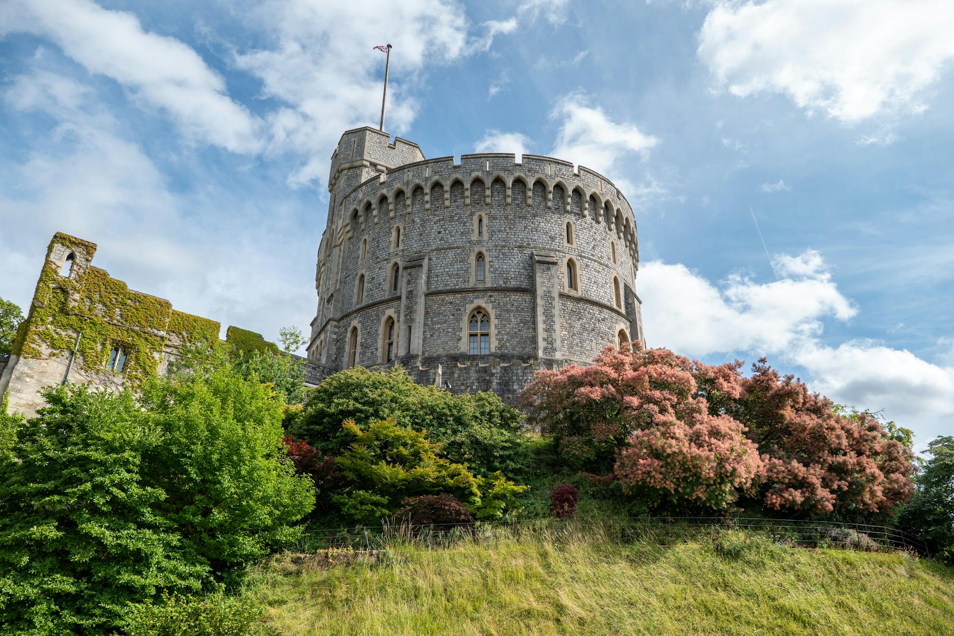 A scenic view of Windsor Castle surrounded by lush greenery and clear skies.