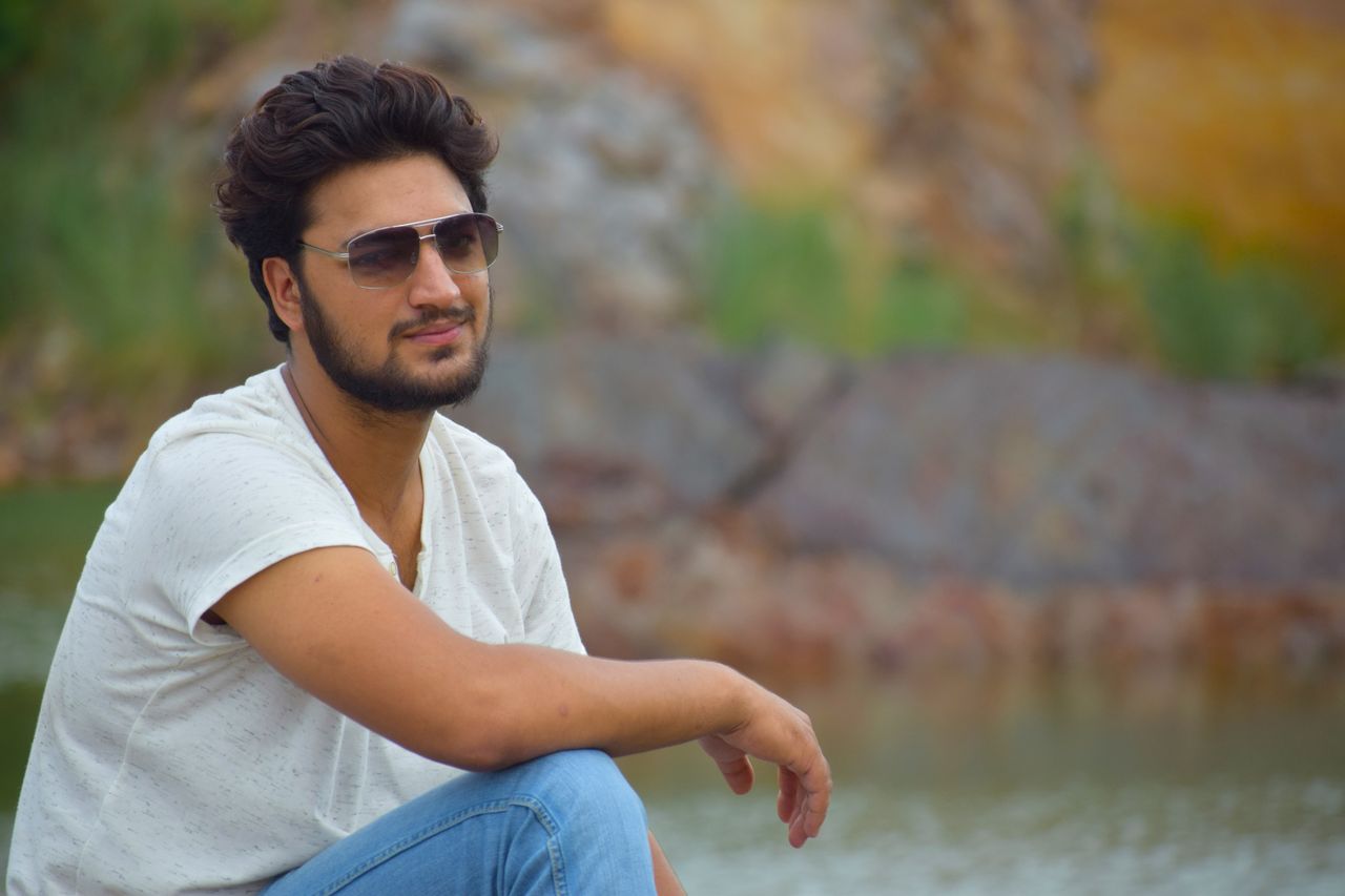 outdoor portrait of a man wearing sunglasses and sitting by a scenic b