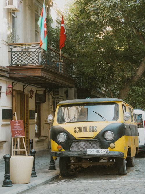 Free A vintage school bus parked on a charming city street with international flags. Stock Photo