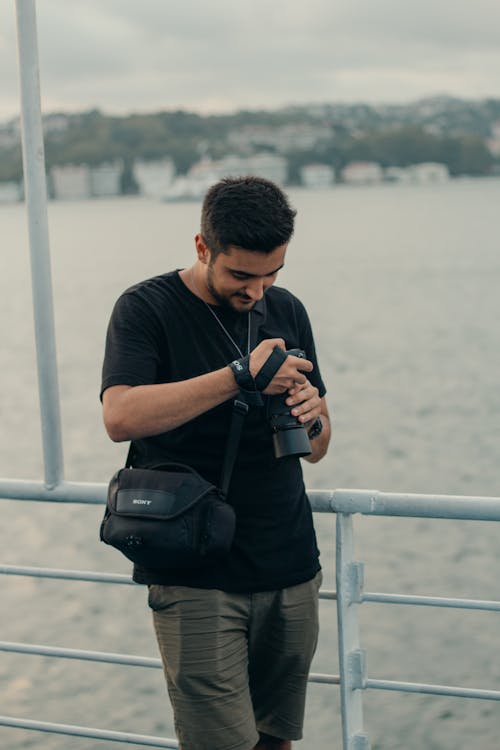 Man Holding a Camera in a Harbor