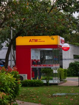 Outdoor ATM booth in Ho Chi Minh City park surrounded by lush greenery and trees.