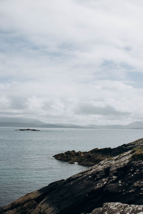 Free Peaceful coastal view with rocky shoreline and calm sea under cloudy sky. Stock Photo