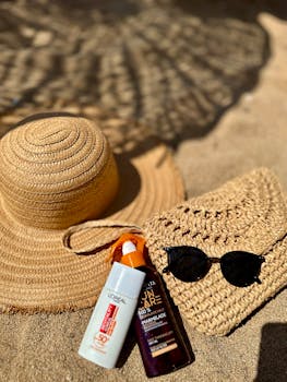 A straw hat, sunglasses, and sunscreen on a sunny beach in Yalova, Türkiye.