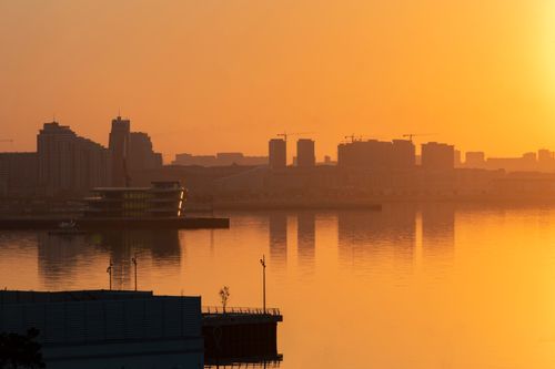 Free A captivating sunset view over Baku's skyline reflecting on the still waters, creating a serene urban landscape. Stock Photo
