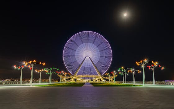 Captivating night view of the illuminated Baku Ferris Wheel under a full moon.