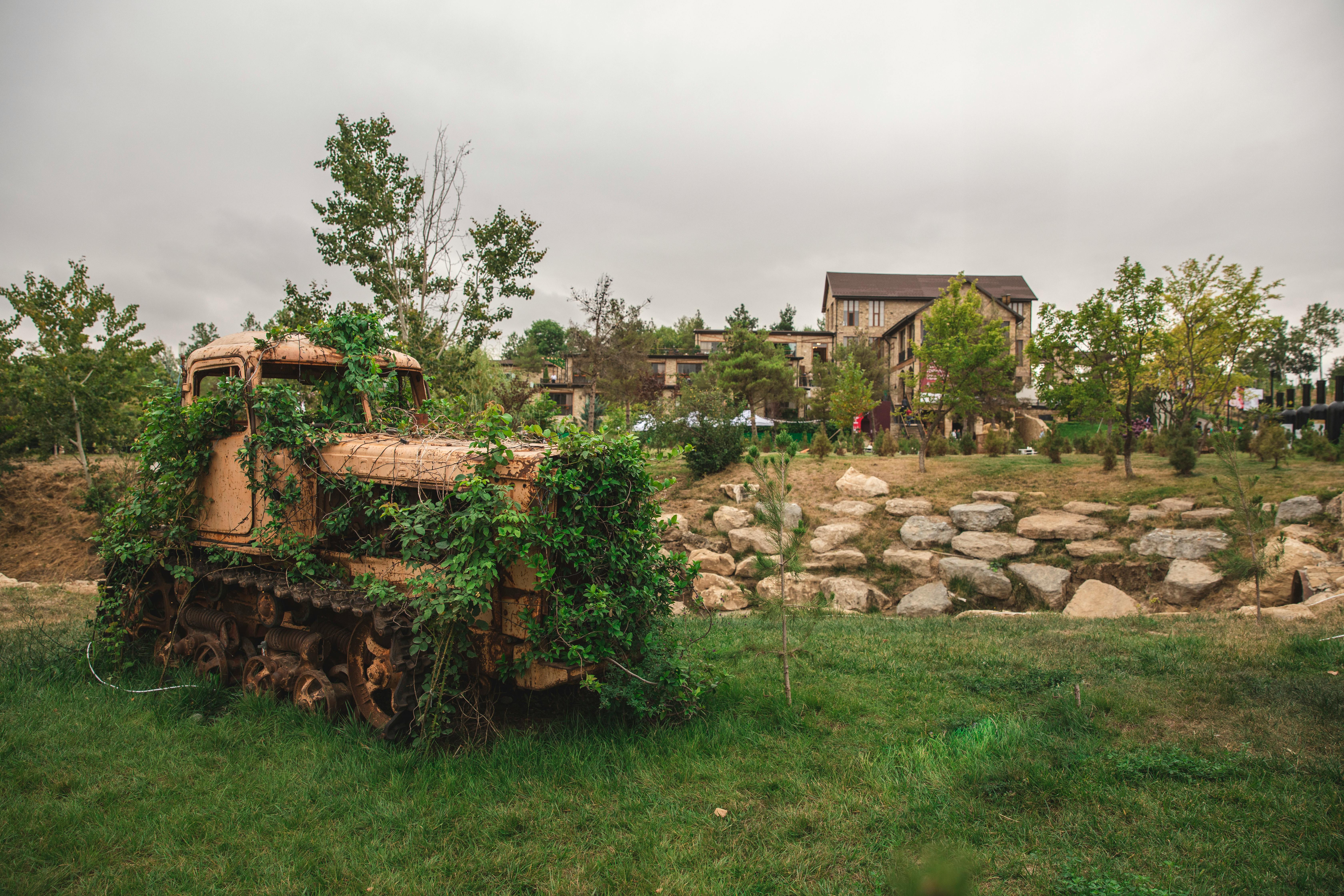 Overgrown rusty tractor in lush green countryside of Shamakhi, Azerbaijan.