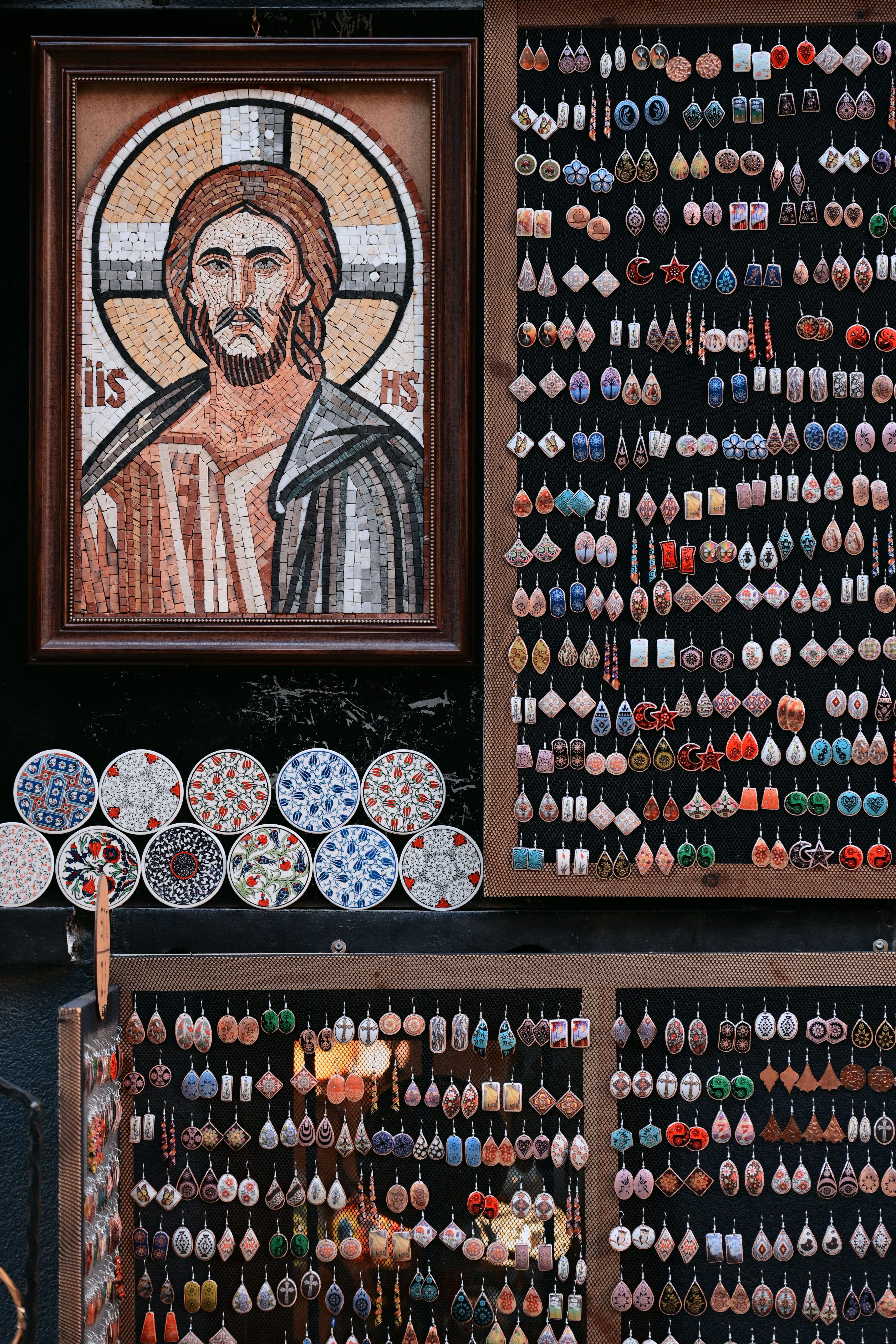 Colorful market stall displaying a mosaic portrait of Jesus and various handmade jewelry.