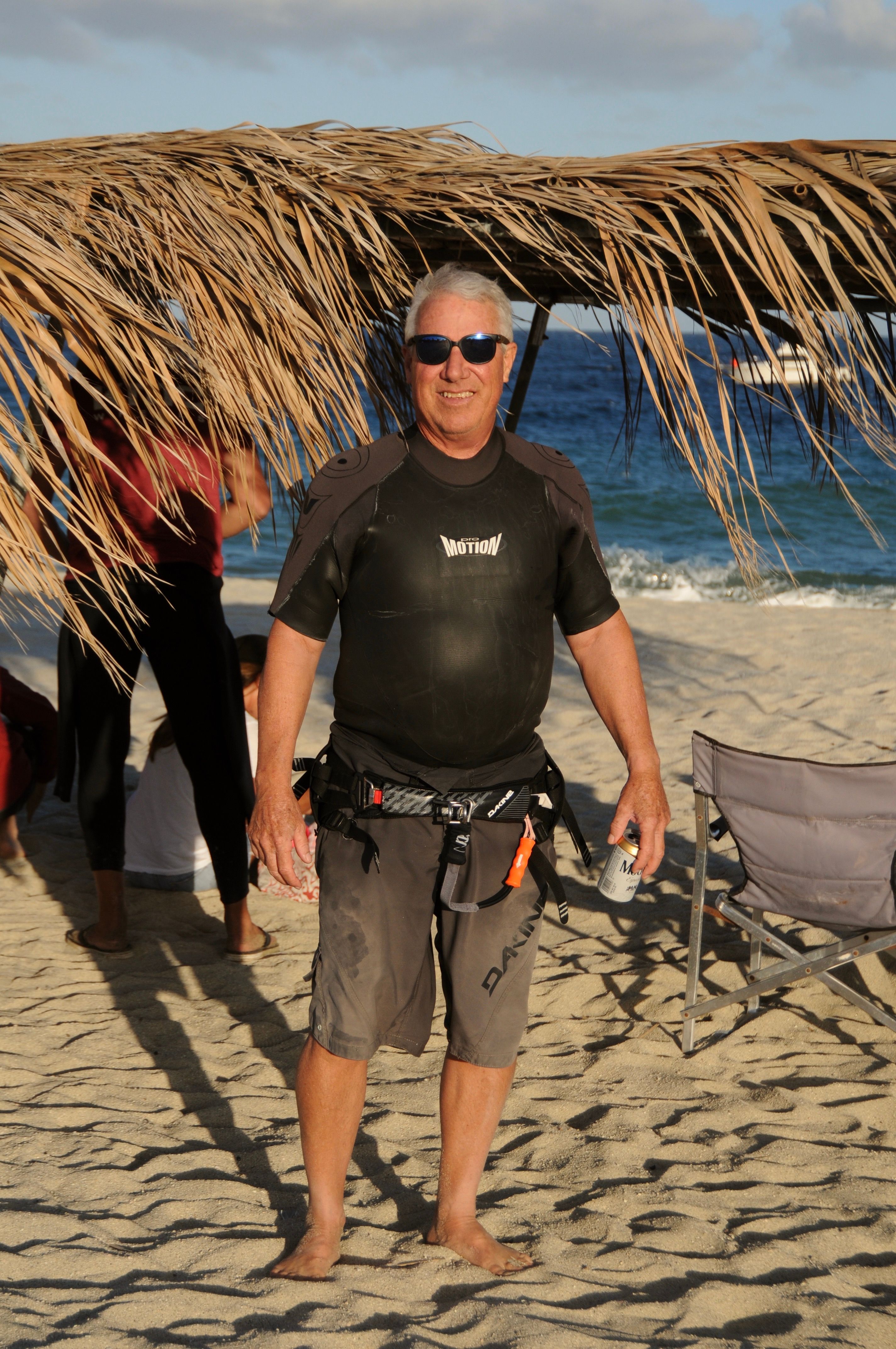 Senior man enjoying a sunny day at the beach in a tropical paradise, wearing sunglasses and smiling.