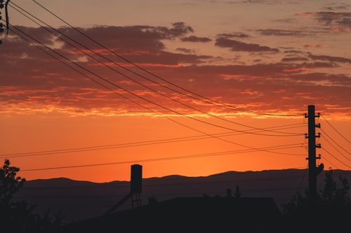 Free A stunning rural sunset with silhouetted power lines and orange sky, evoking tranquility. Stock Photo