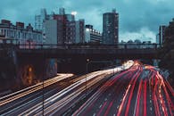 在多云的夜空下，长镜头捕捉到城市交通形成的彩色光条纹