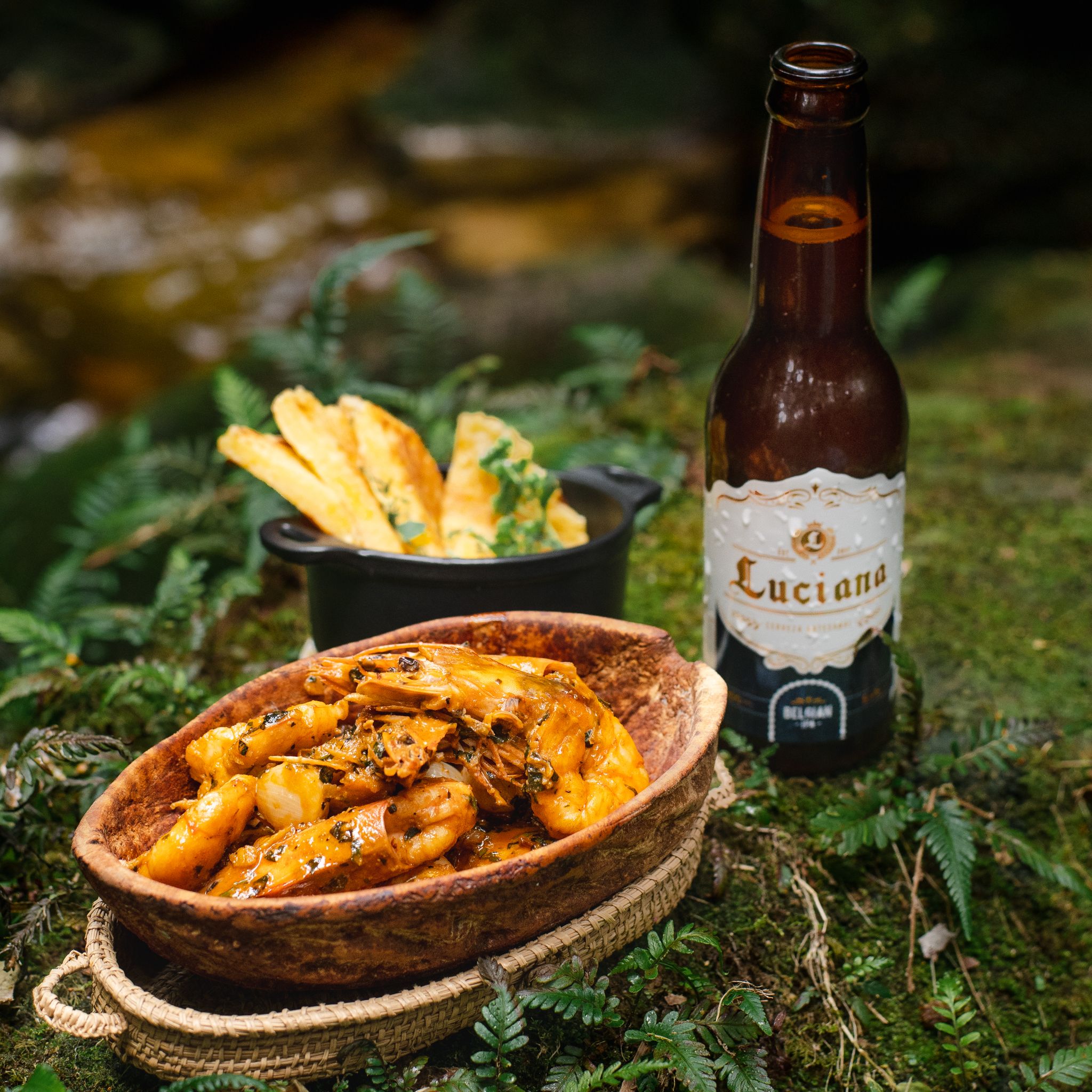 A delicious shrimp dish paired with Belgian beer outdoors on a mossy surface.