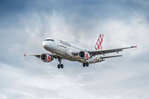 Free A Volotea commercial airplane flying through a cloudy sky, captured from below. Stock Photo