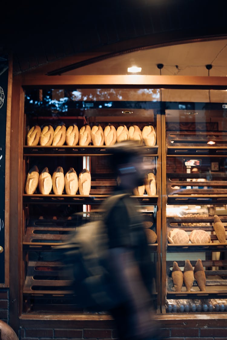 Person Walking Near Shelves With Bread In Bakery