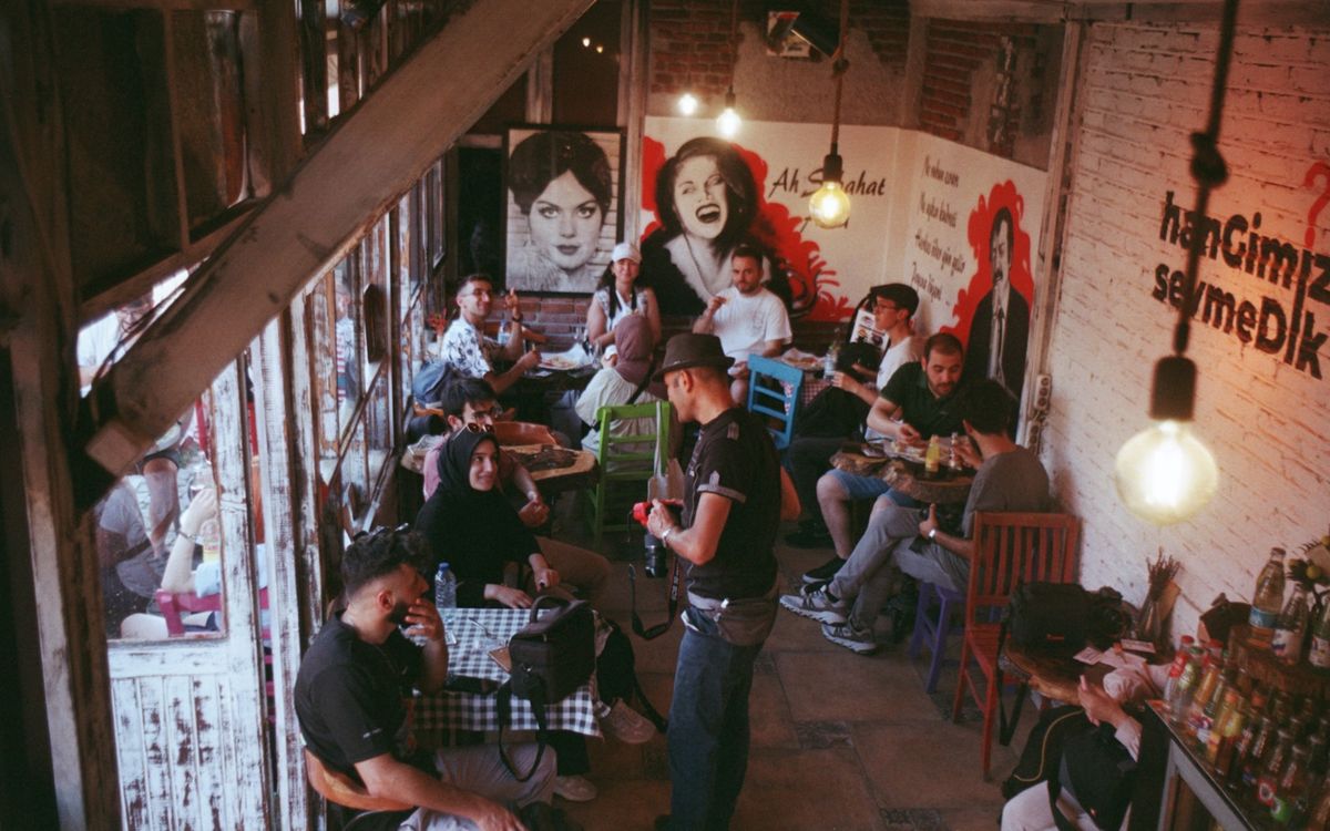 A lively and vibrant café setting with friends gathering, featuring art-filled walls and a casual atmosphere.