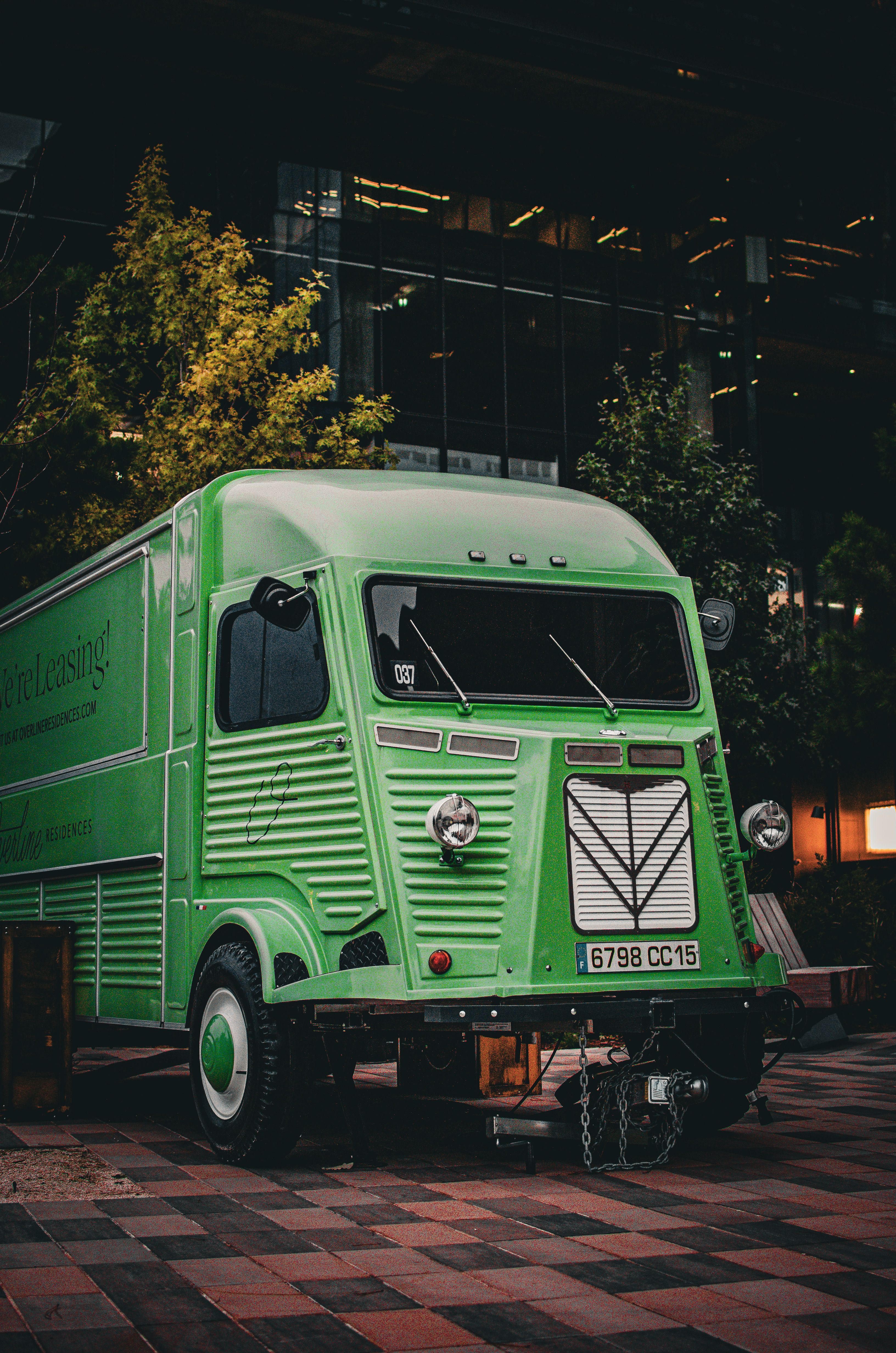 Vintage green Citroen H Van parked in a cityscape setting at night, highlighting urban ambiance.