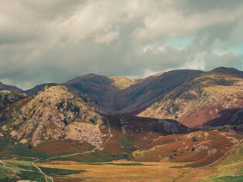 Free Breathtaking view of rugged mountains and lush valleys beneath dramatic sky. Stock Photo