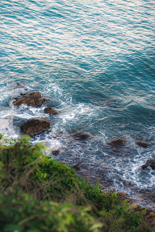 Free A beautiful view of the Vietnamese coastline with waves crashing against rocks and lush greenery. Stock Photo