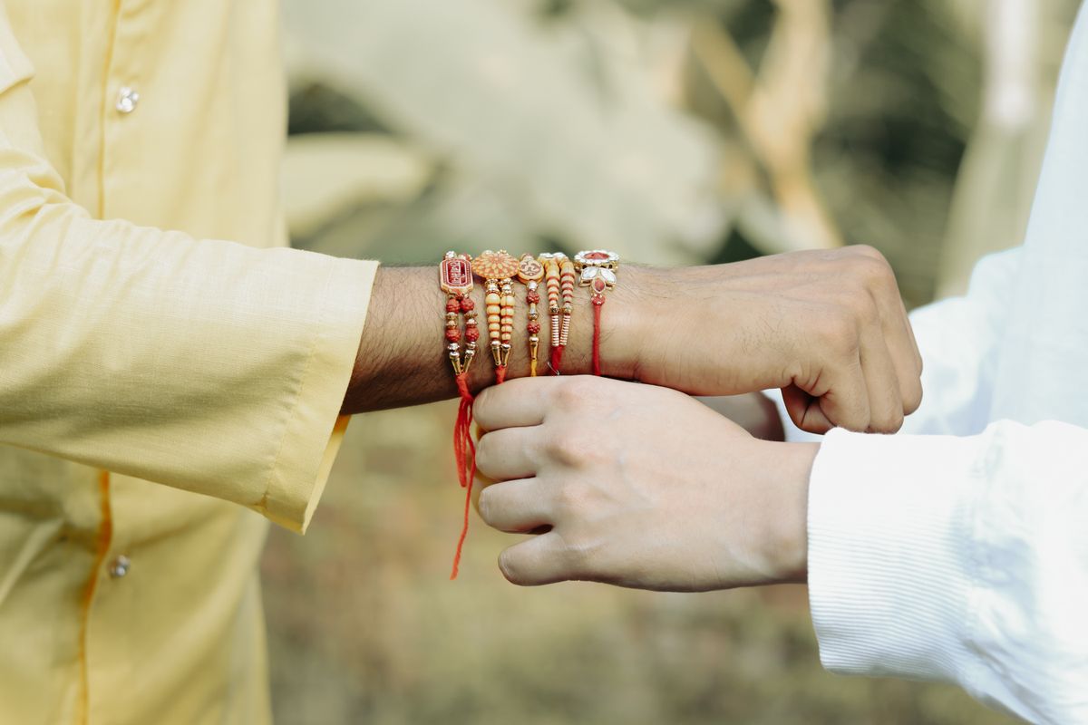 Two friends exchanging rakhi threads, close-up of hands