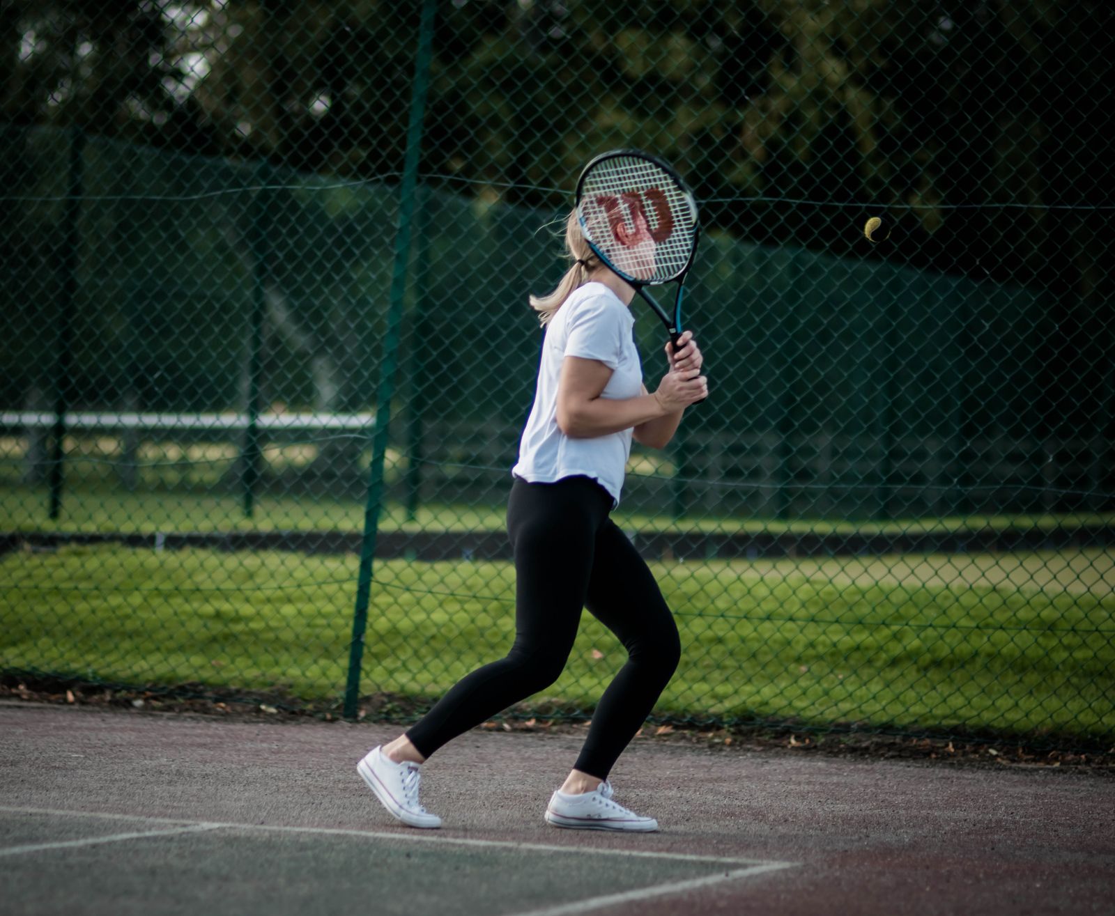 Active older woman playing tennis on a private outdoor court