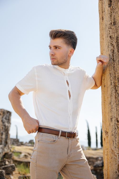 Free A man in casual attire poses confidently by ancient ruins in Türkiye. Stock Photo