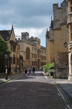 Charming view of historic buildings and pedestrians on Merton Street, Oxford, during a summer day.