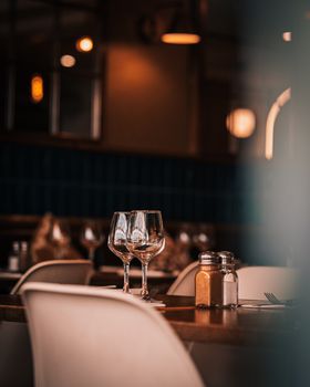 Warmly lit Parisian restaurant showcasing elegant table setting with wine glasses.