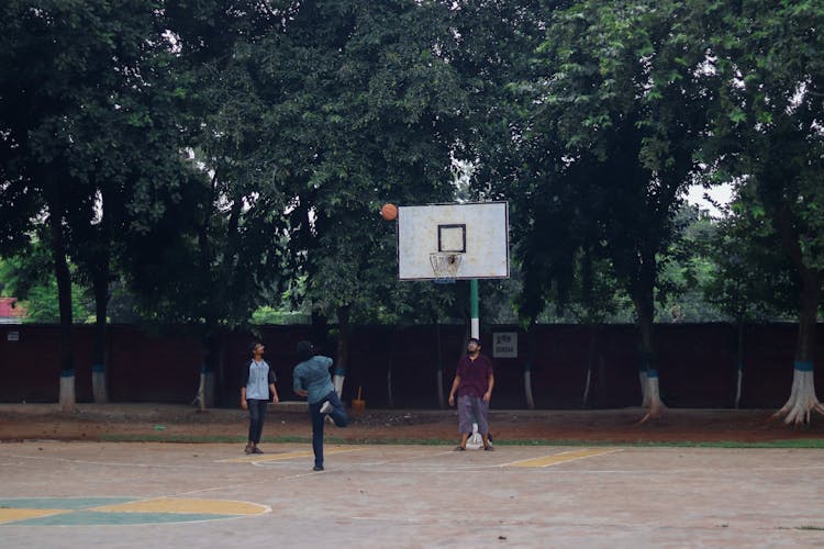 Young Men Playing Basketball In A Courtyard