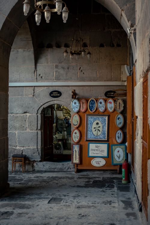 Free A collection of framed artworks on display in an arched stone passage. Stock Photo