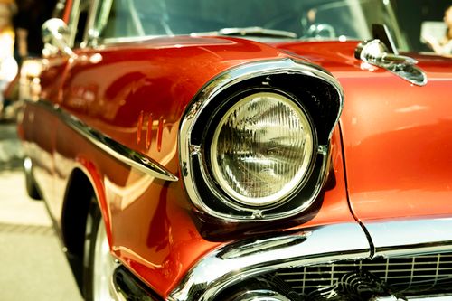 Free Close-up shot of a classic red vintage car showcasing its chrome details and headlight. Stock Photo