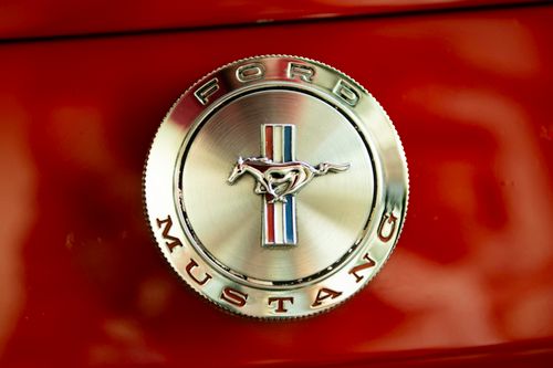 Free Close-up of a classic Ford Mustang emblem on a red background, showcasing vintage automotive design. Stock Photo