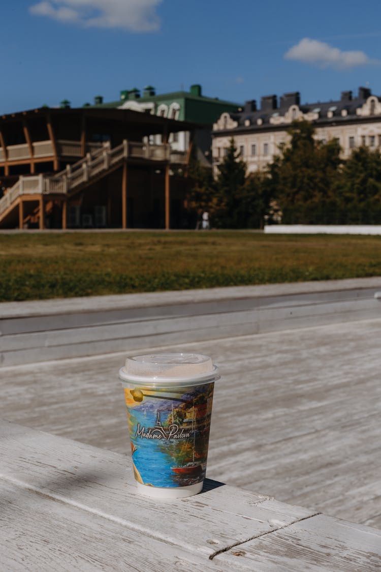 Takeout Cup Set On Wooden Planks Overlooking Mansion