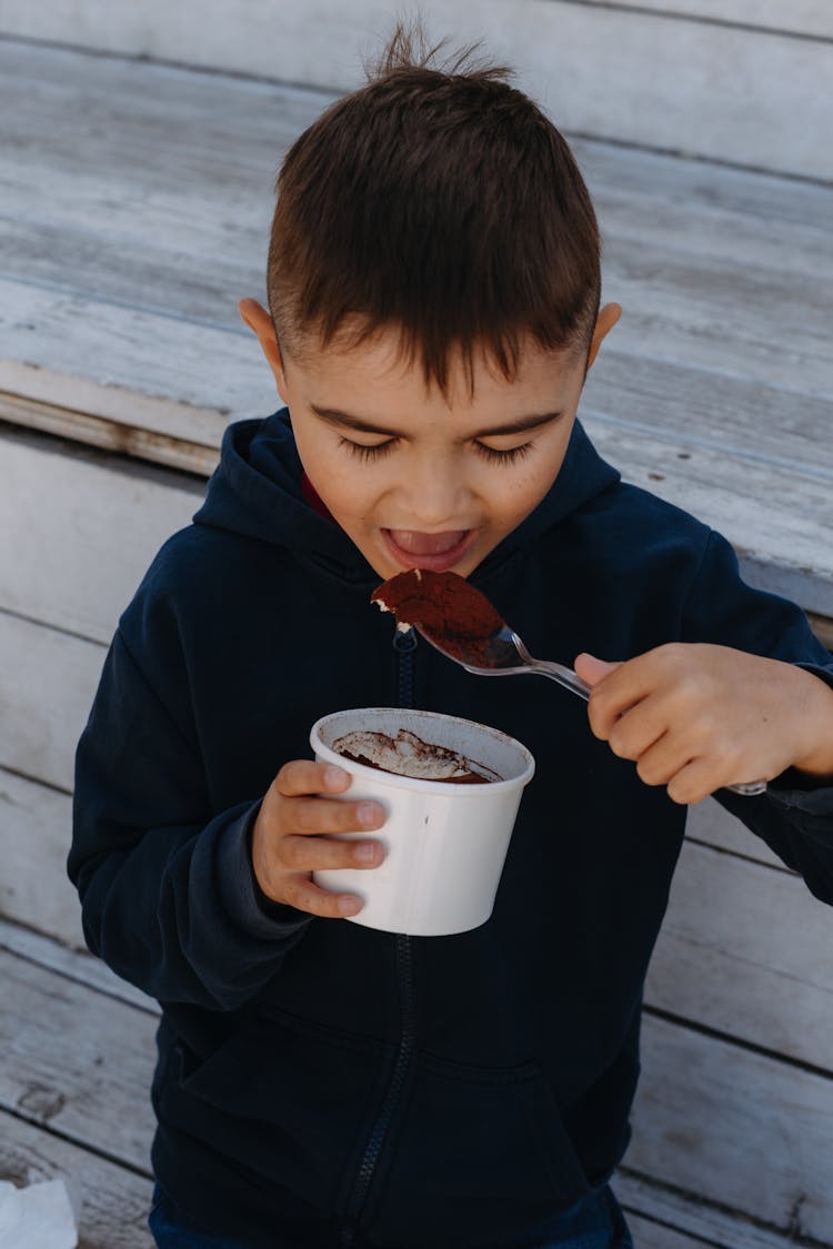 Little Boy Eating Ice Cream From Takeout Cup