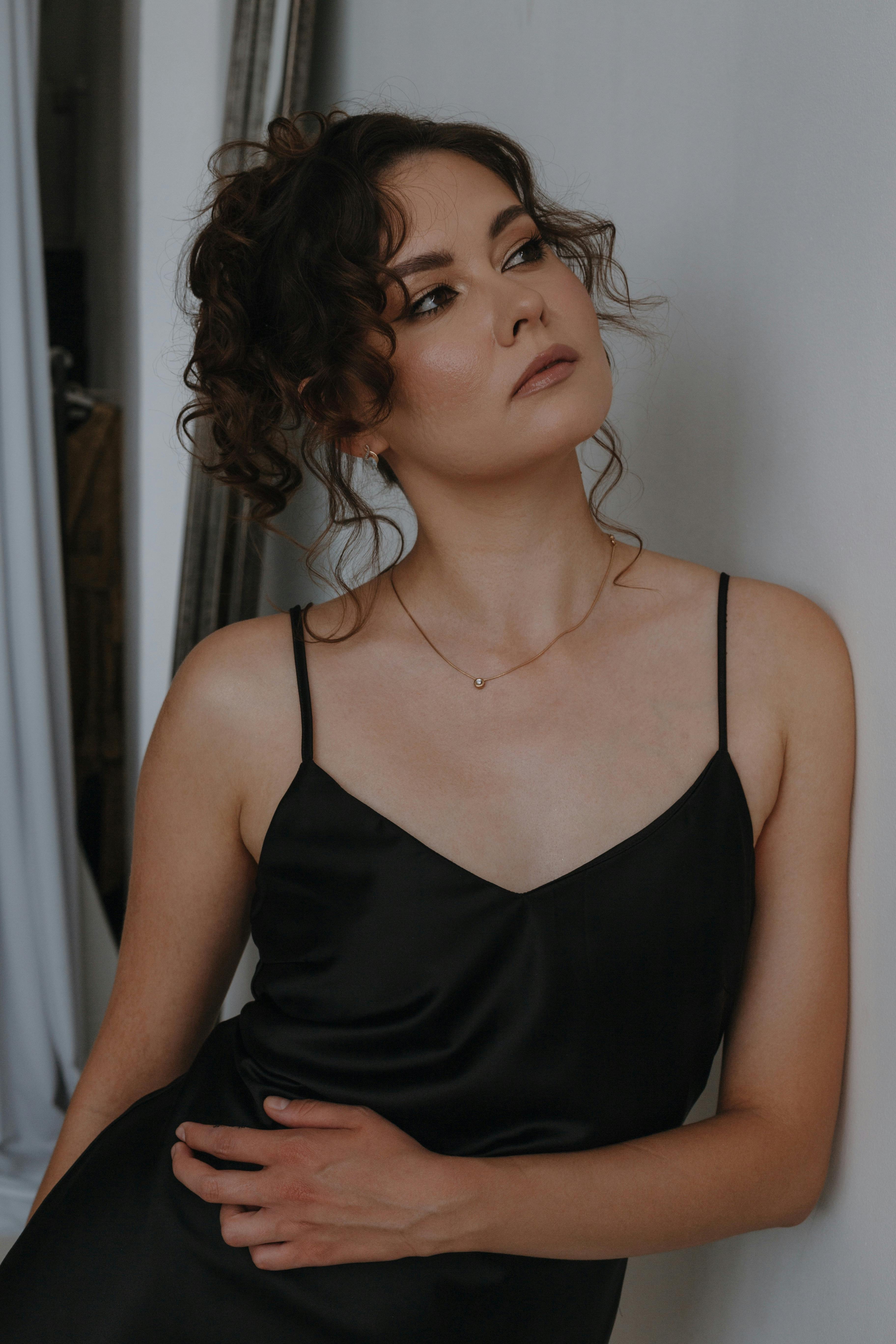 一位身穿黑色连衣裙、留着时尚发型的年轻女子在室内优雅地摆姿势的肖像