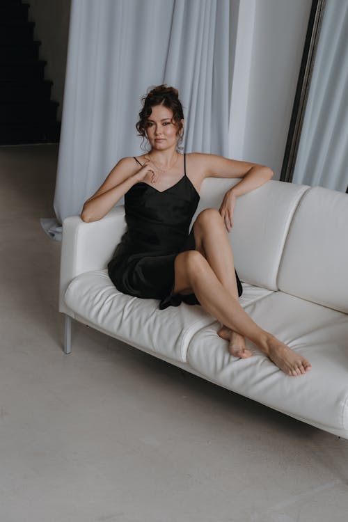 Woman in Spaghetti Straps Dress Sitting on Sofa