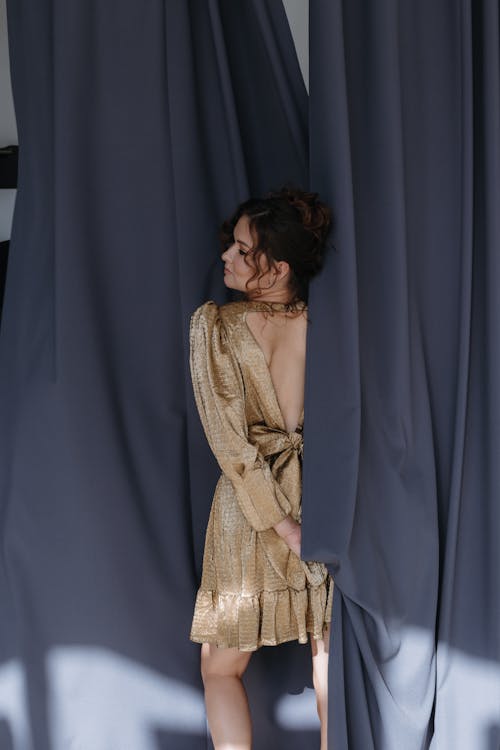 Brunette Woman in Dress Standing Between Curtains