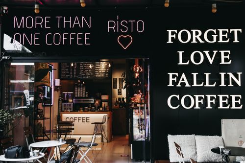 Free Trendy café interior with neon signs and cozy coffee setup, perfect for urban relaxation. Stock Photo