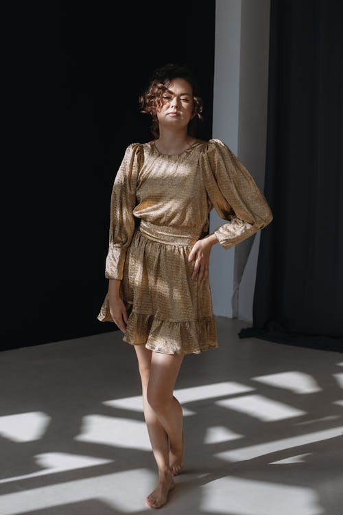 Brunette Woman Posing in Golden Mini Dress with Flared Sleeves