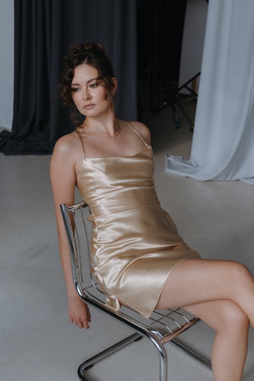 Relaxed Woman in Spaghetti Strap Dress Sitting on Modern Chair
