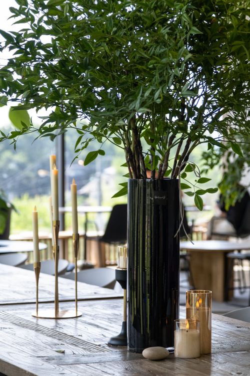 Free A stylish table setting featuring a tall vase with greenery and elegant candles for a modern, sophisticated ambiance. Stock Photo
