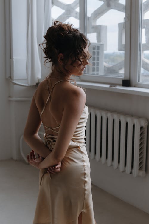 Beautiful Elegant Woman in Dress Standing Near Windows