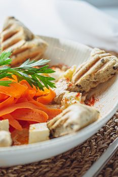 Close-up of a vibrant vegetable salad garnished with cheese and herbs in a white bowl.