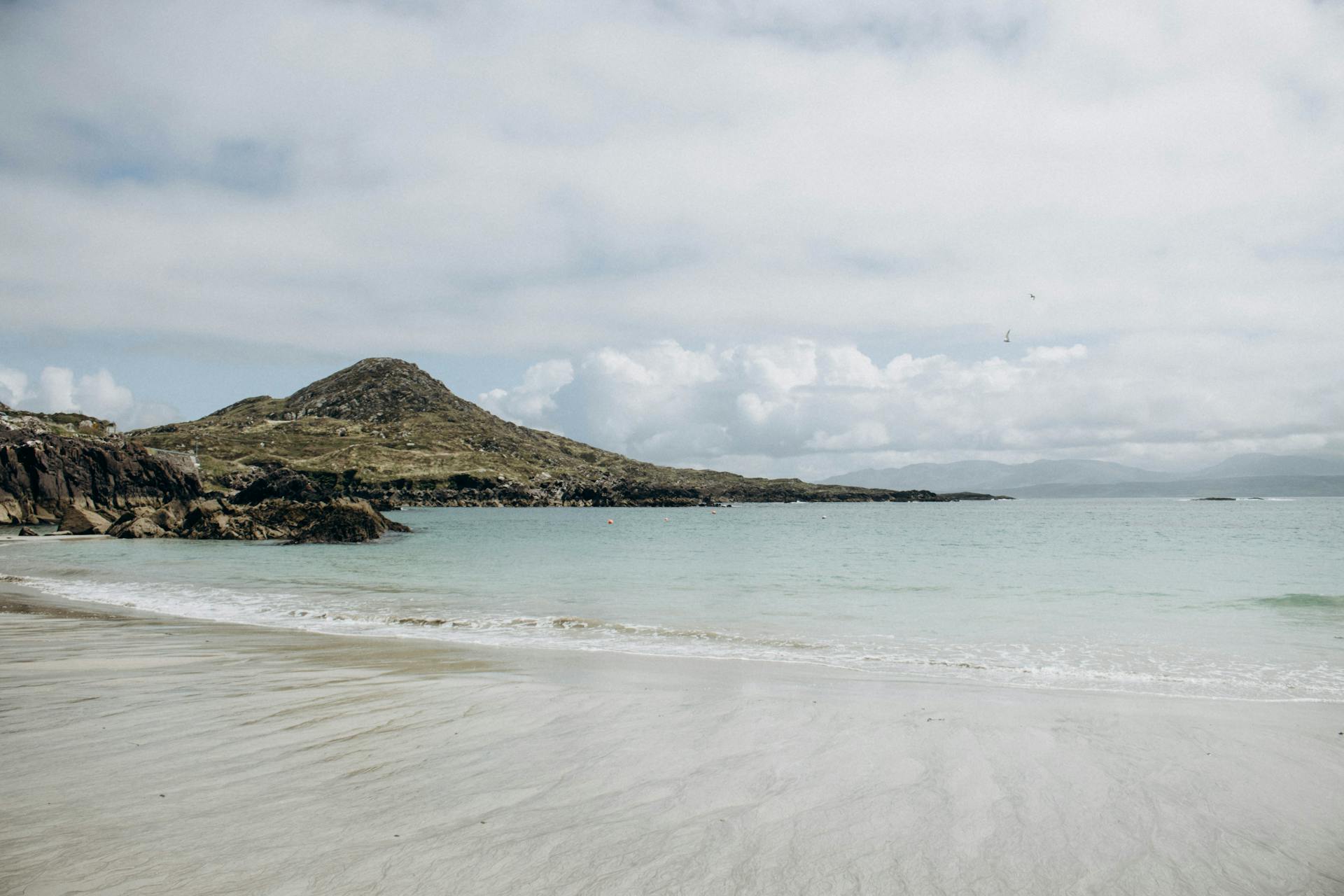 Peaceful seascape with sandy beach and mountains at O Carroll Cove, Ireland.