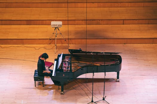 A musician plays a grand piano on stage during a classical concert from an elevated view.