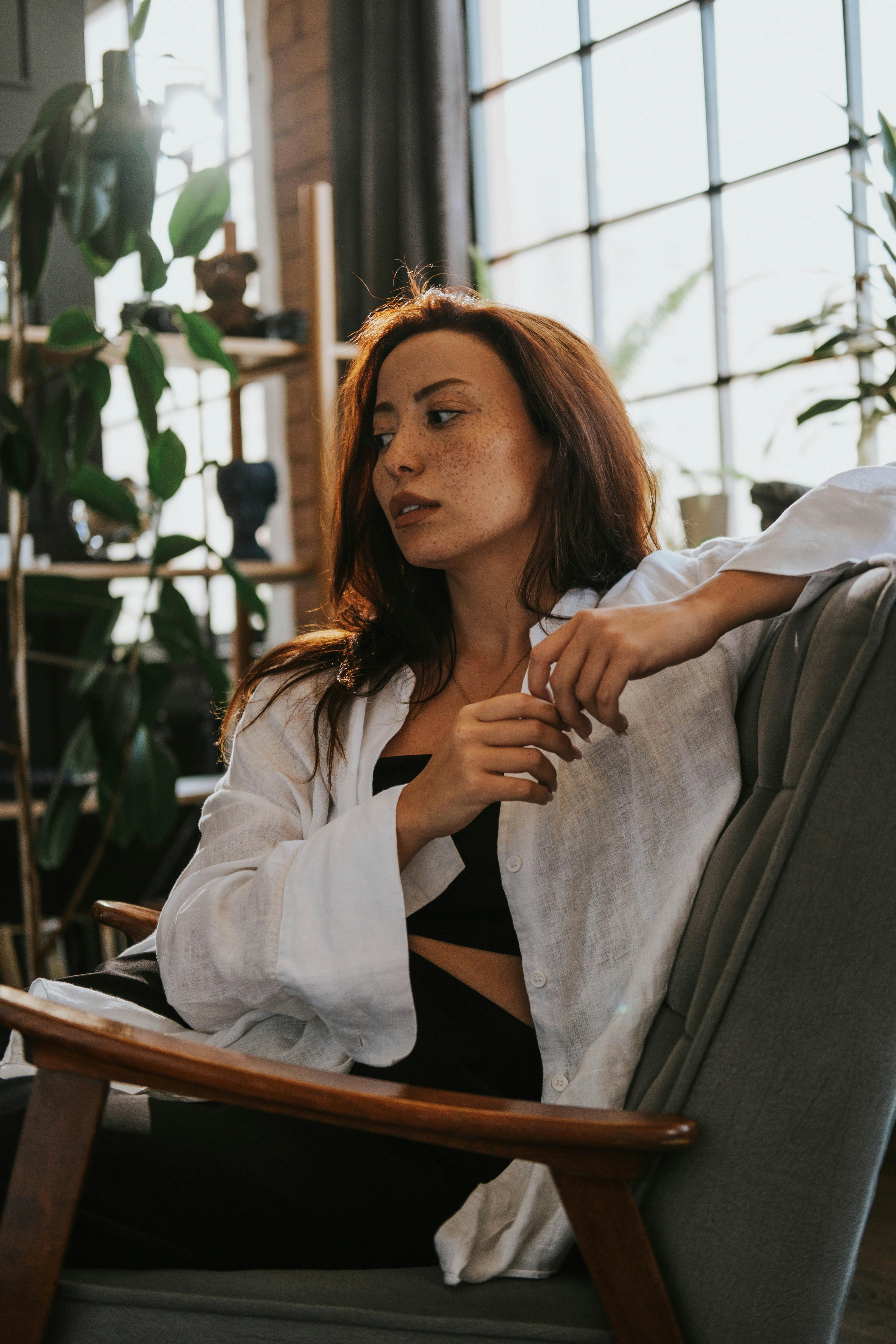 Young woman in a white shirt relaxing indoors. Modern fashion portrait photography.