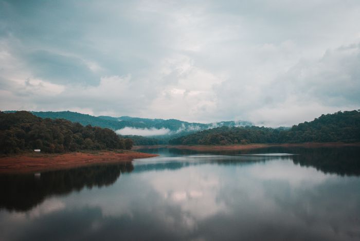 Calm Periyar Lake with misty green hills reflected in peaceful waters