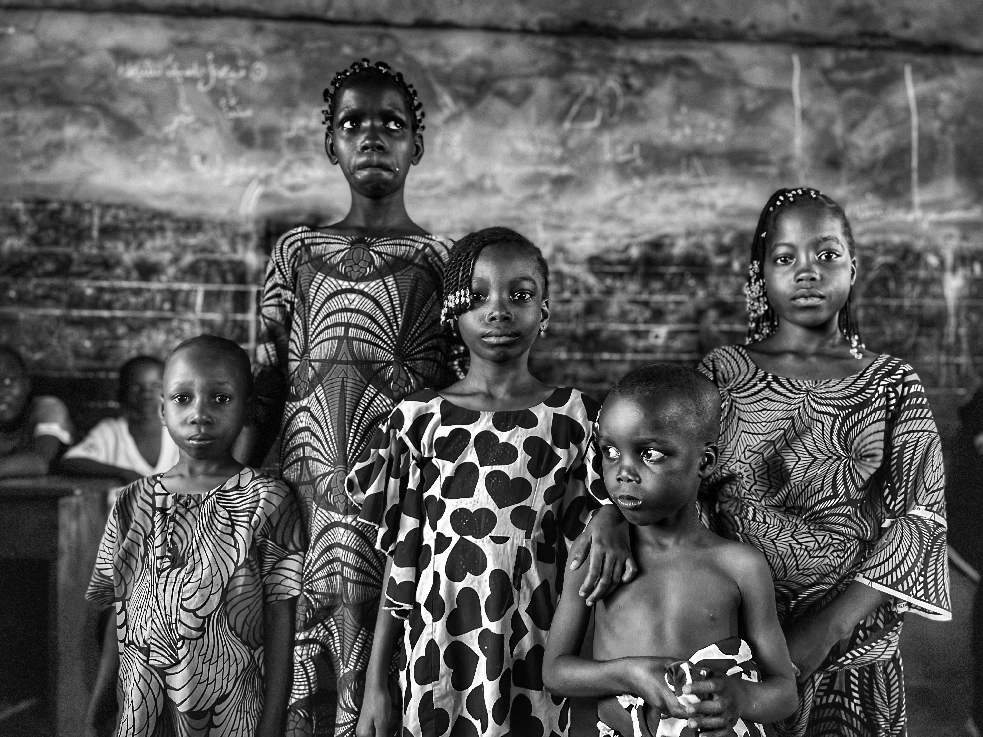 Black and white photo of African children posing in a classroom, reflecting unity and culture.